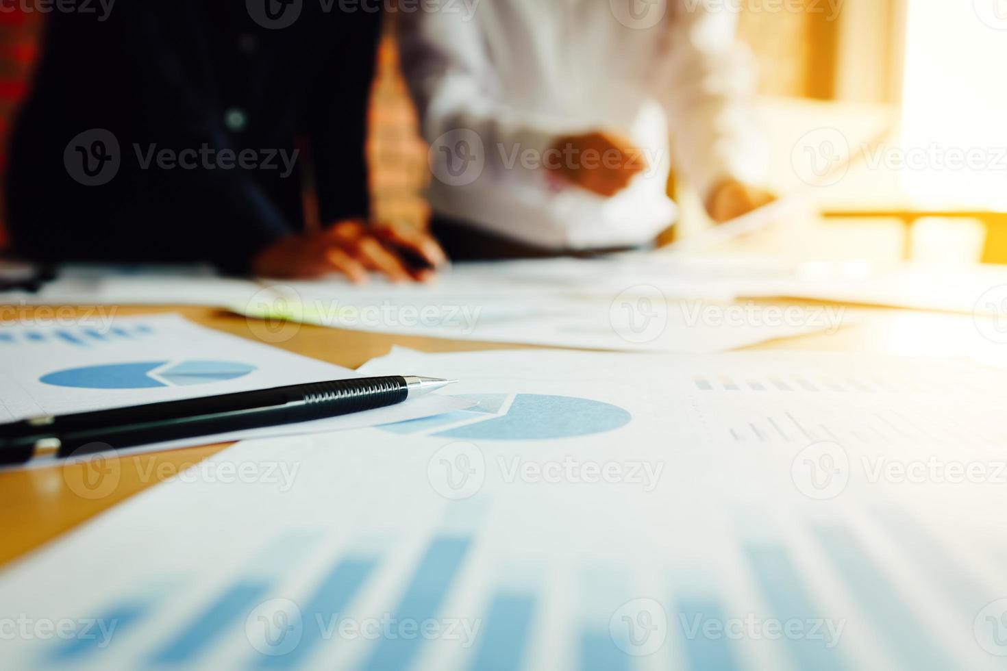 Summary report graph and two businessmen in a meeting and standing at boardroom table background. photo
