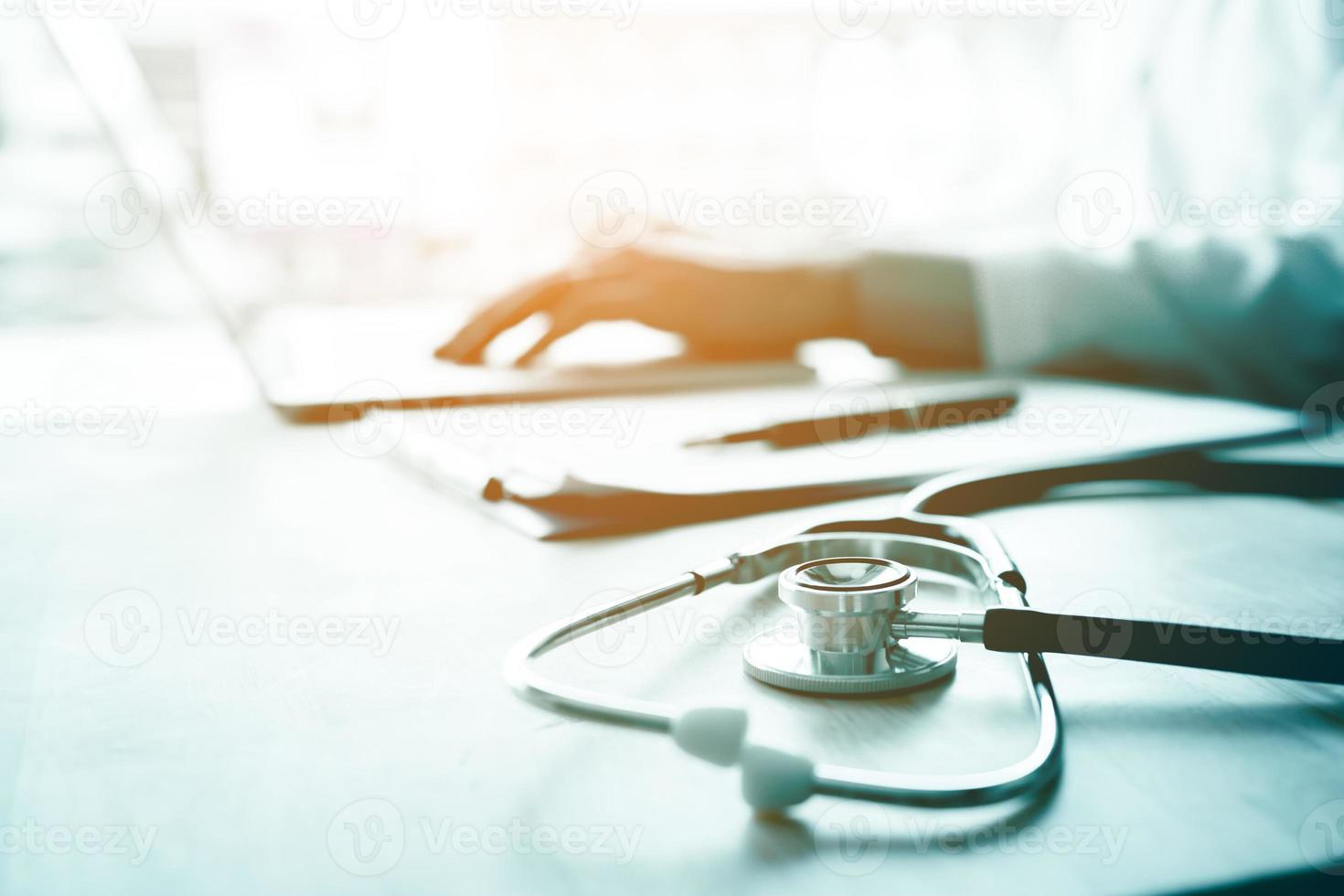 Doctor using laptop at desk in clinic working on computer at room office. photo