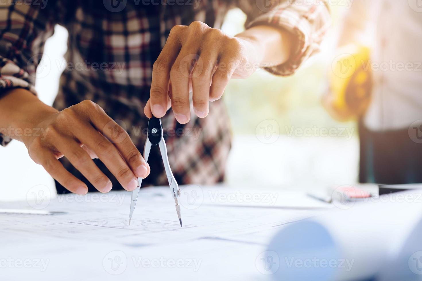 Engineering man working on blueprint in workplace and drawing compass. photo