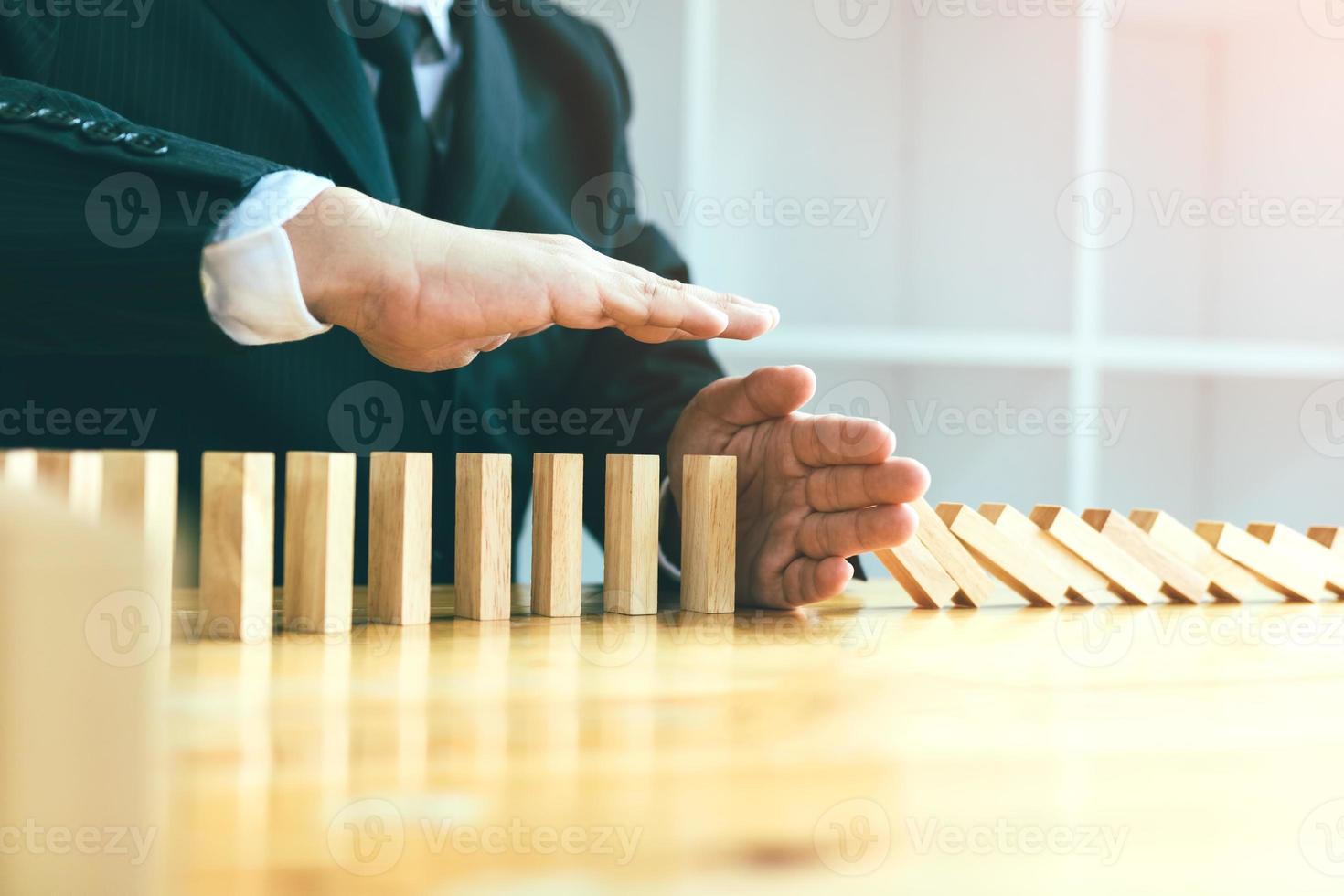 Risk concept with hand of businessman stopping and protection the domino effect. photo