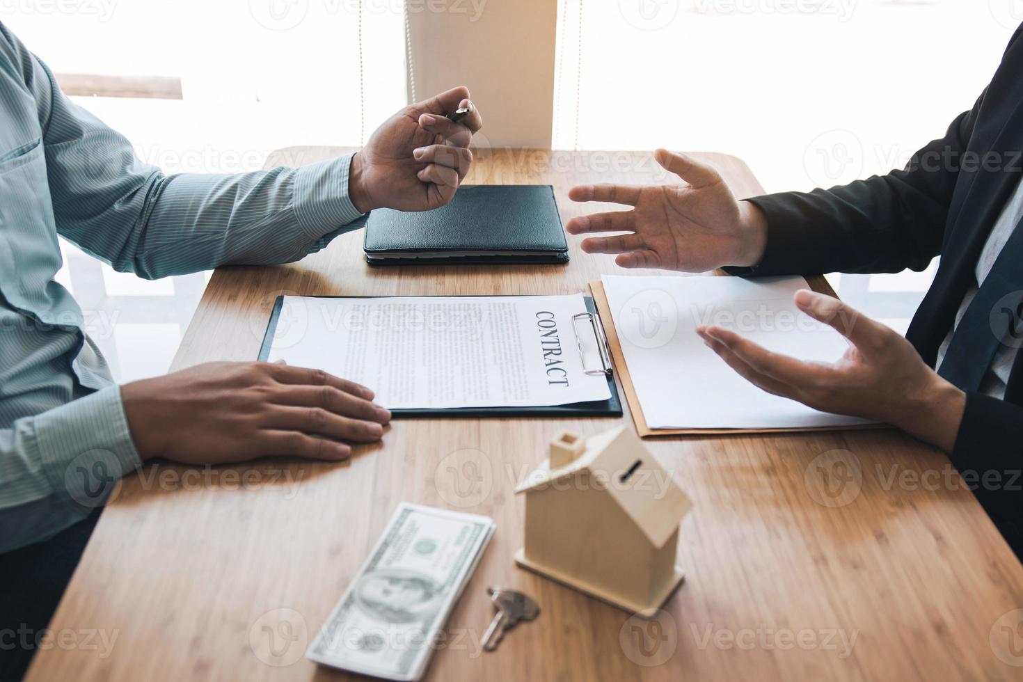 el corredor de ventas de casas de gente de negocios está usando un bolígrafo que apunta al modelo de la casa y describe los diversos componentes de la casa. foto