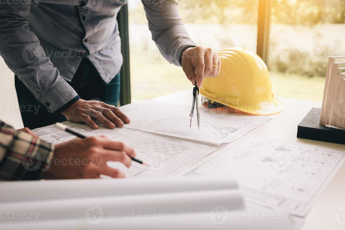 Two entrepreneur architect hand holding compass over some building blueprint. photo