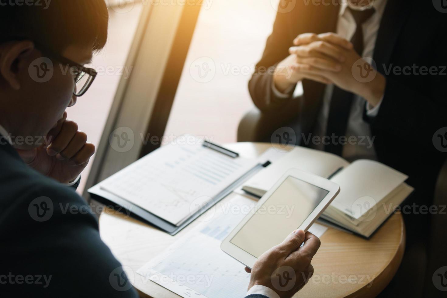 Business partnership coworkers using a tablet to chart company financial statements report and profits work progress and planning in office room. photo