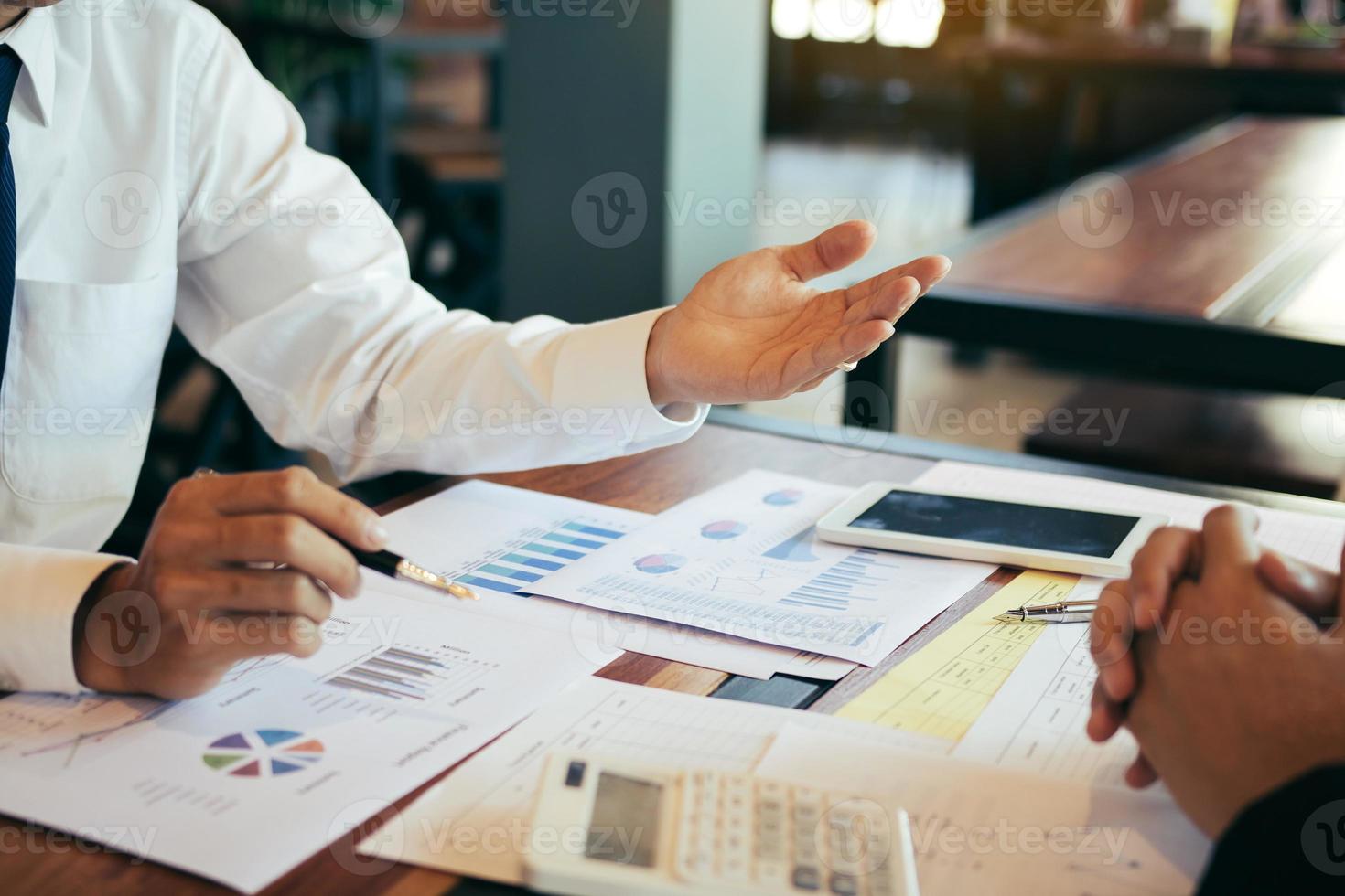 The accounting staff of the company are jointly analyzing the graph of the expenses on the desk in the office. photo