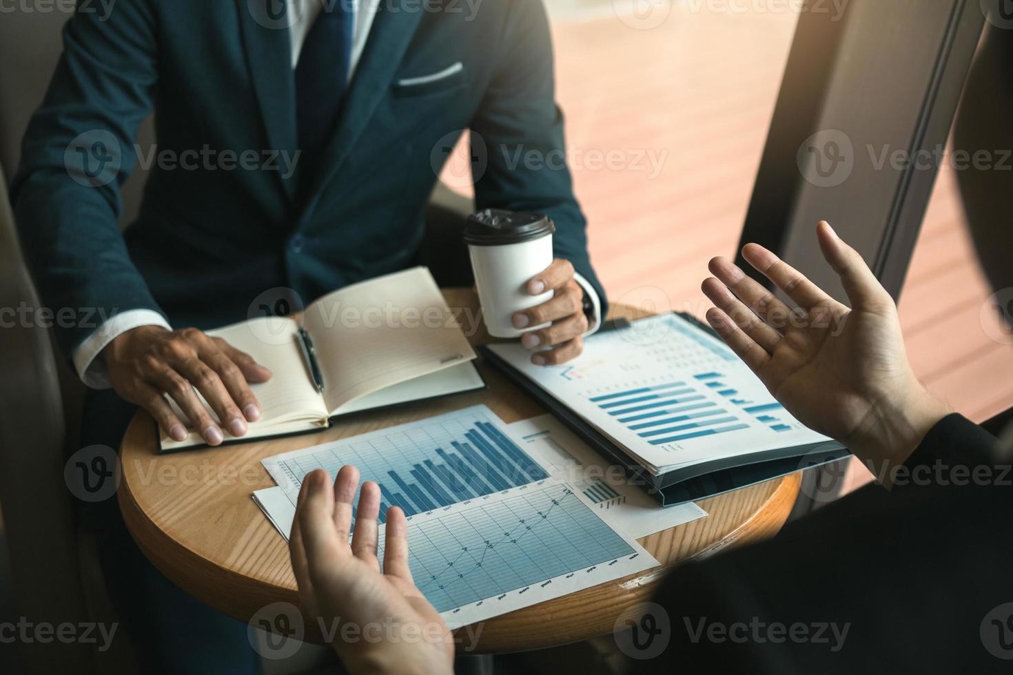 Two business partnership coworkers analysis cost work progress and gesturing with discussing a financial planning graph and company financial during a budget meeting in office room. photo
