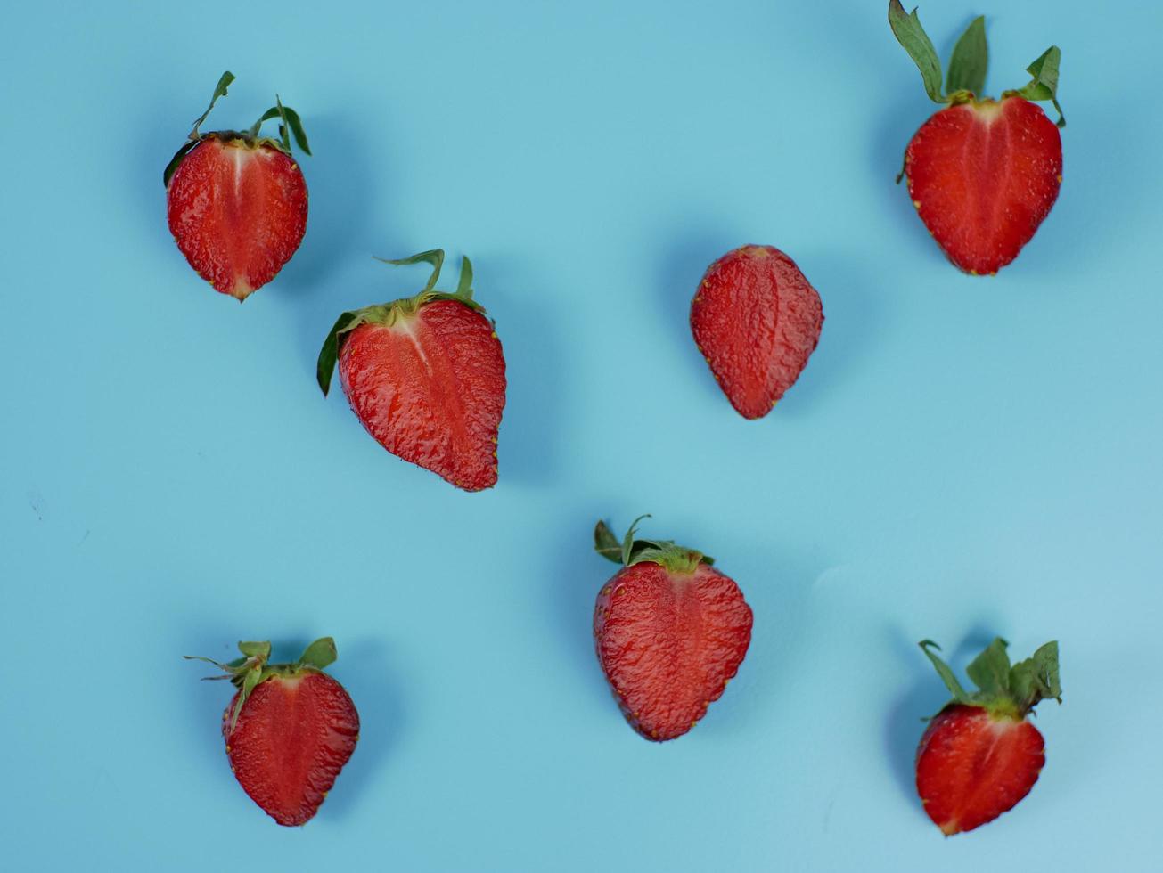 fresh strawberry slices on blue background. flat lay photo