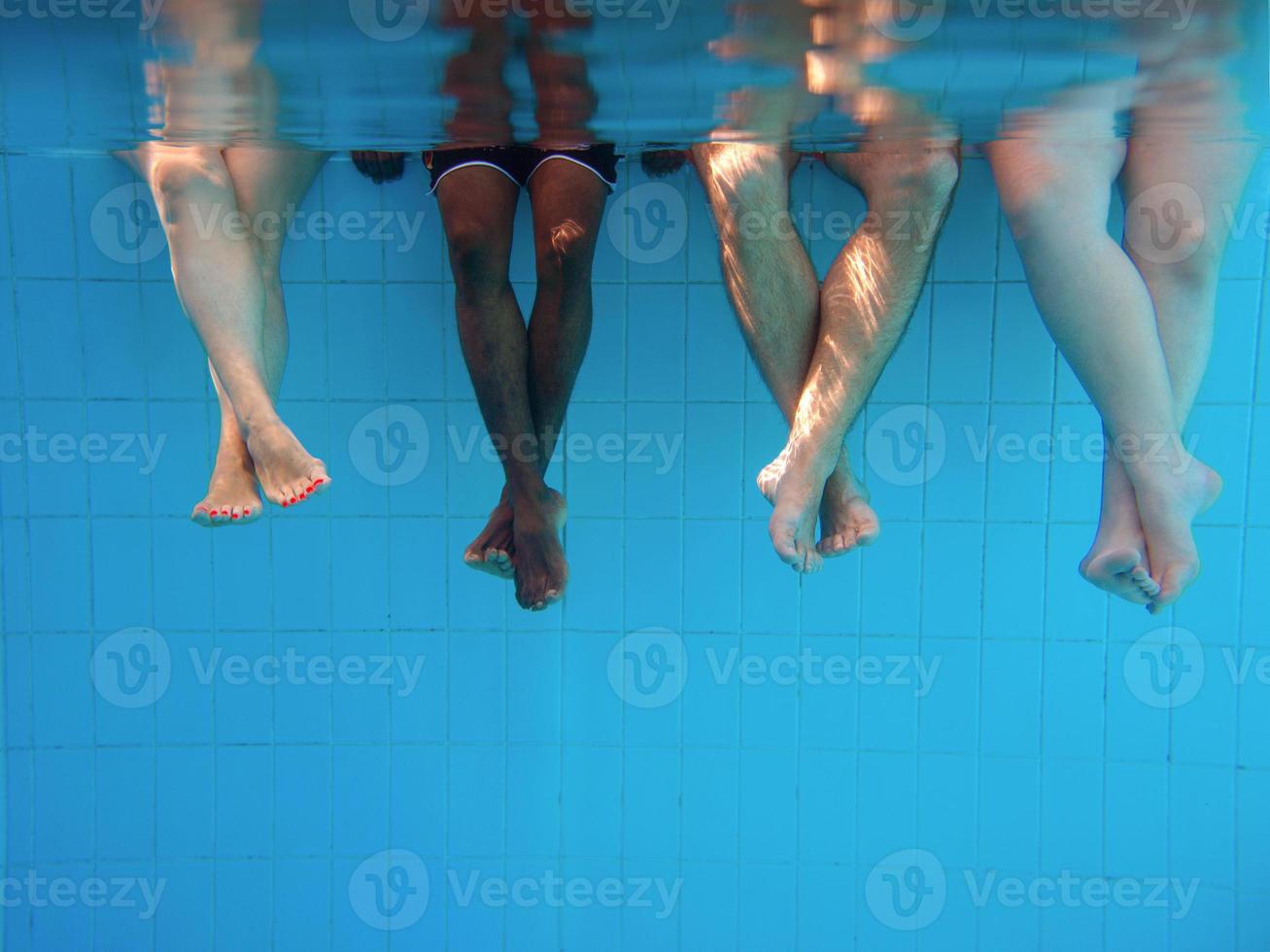 Legs of African American man with caucasian friends in swimming pool underwater. Summer. Vacation, international and sport concept. photo