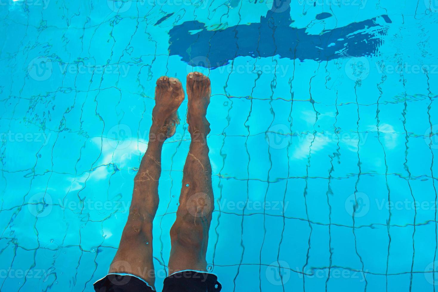 Las piernas de un hombre afroamericano adulto bajo el agua en la piscina foto