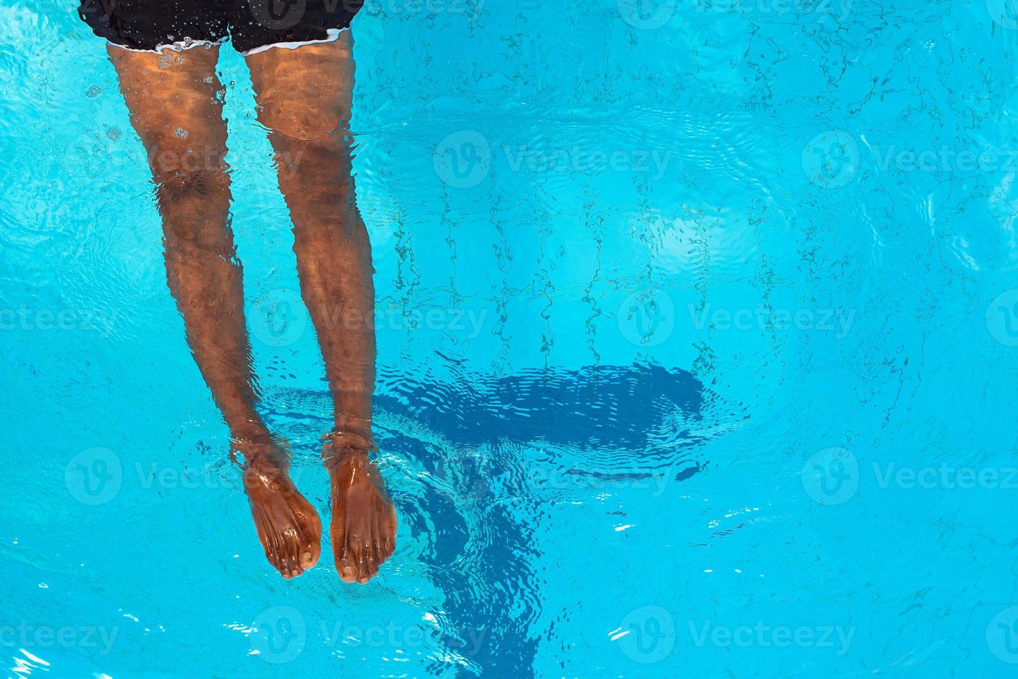 adult African American man's legs underwater in swimming pool photo