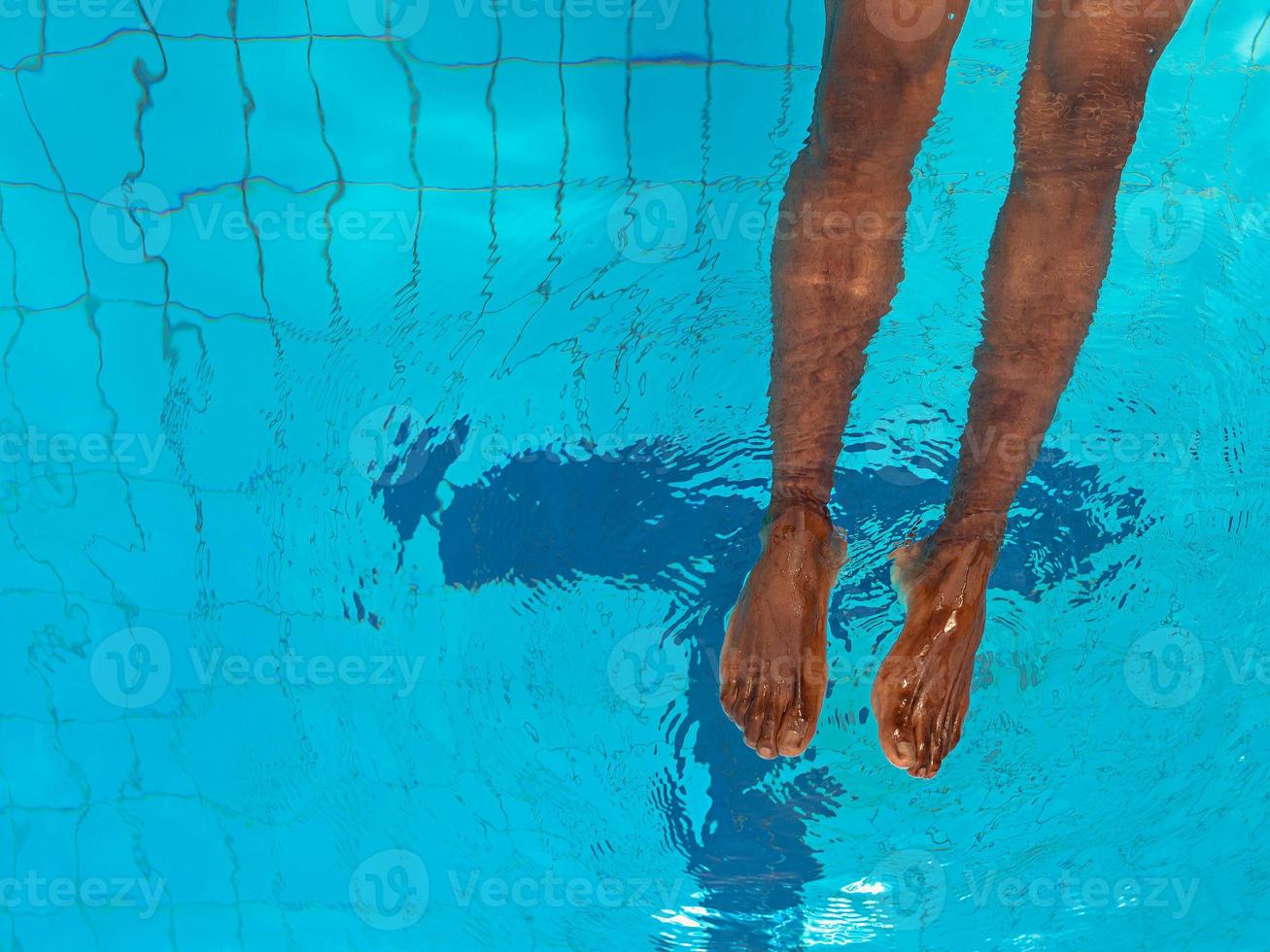 Las piernas de un hombre afroamericano adulto bajo el agua en la piscina foto