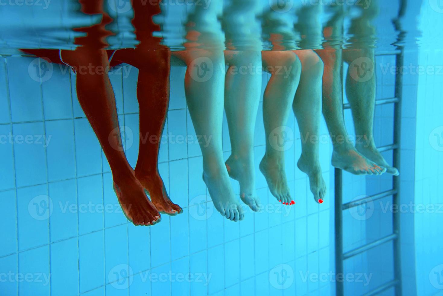 Legs of African American man with caucasian friends in swimming pool underwater. Summer. Vacation, international and sport concept. photo