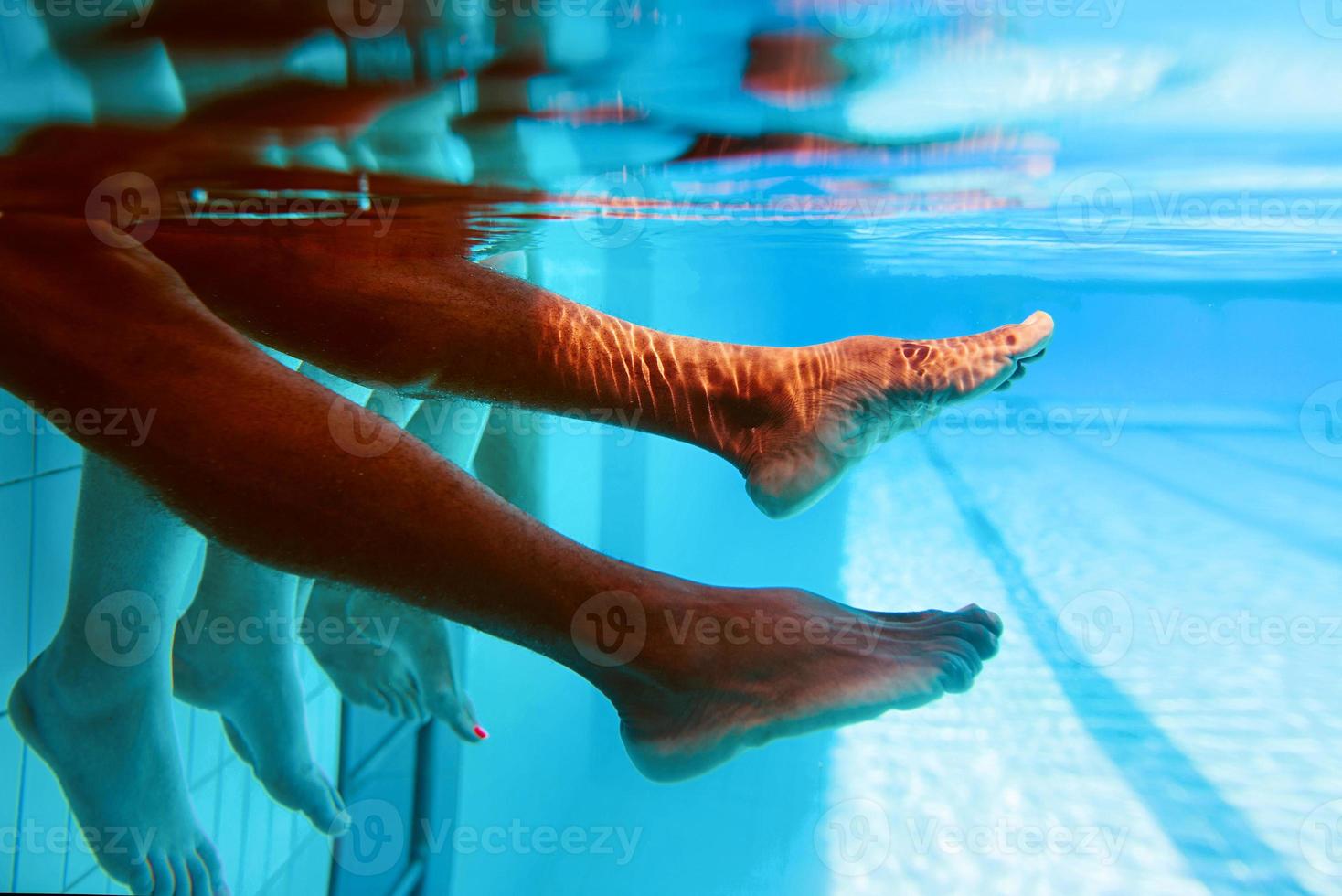 Legs of African American man with caucasian friends in swimming pool underwater. Summer. Vacation, international and sport concept. photo