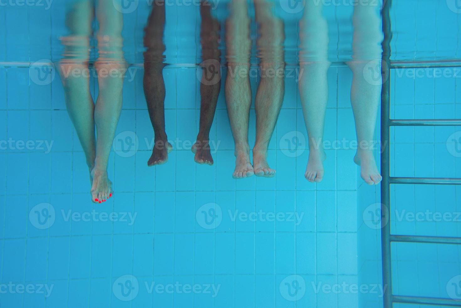 Legs of African American man with caucasian friends in swimming pool underwater. Summer. Vacation, international and sport concept. photo