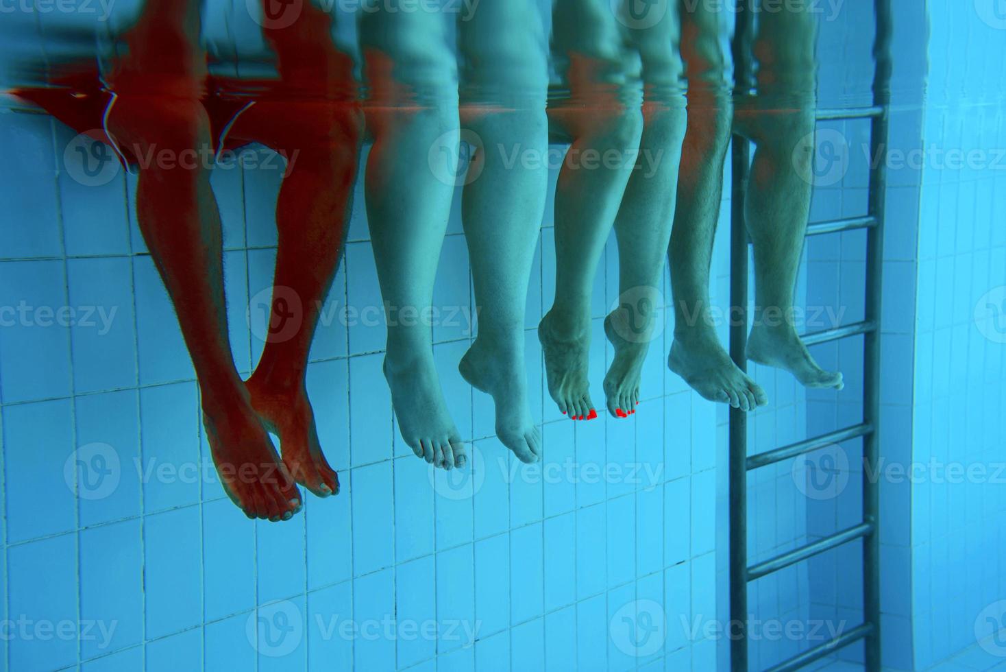 Legs of African American man with caucasian friends in swimming pool underwater. Summer. Vacation, international and sport concept. photo