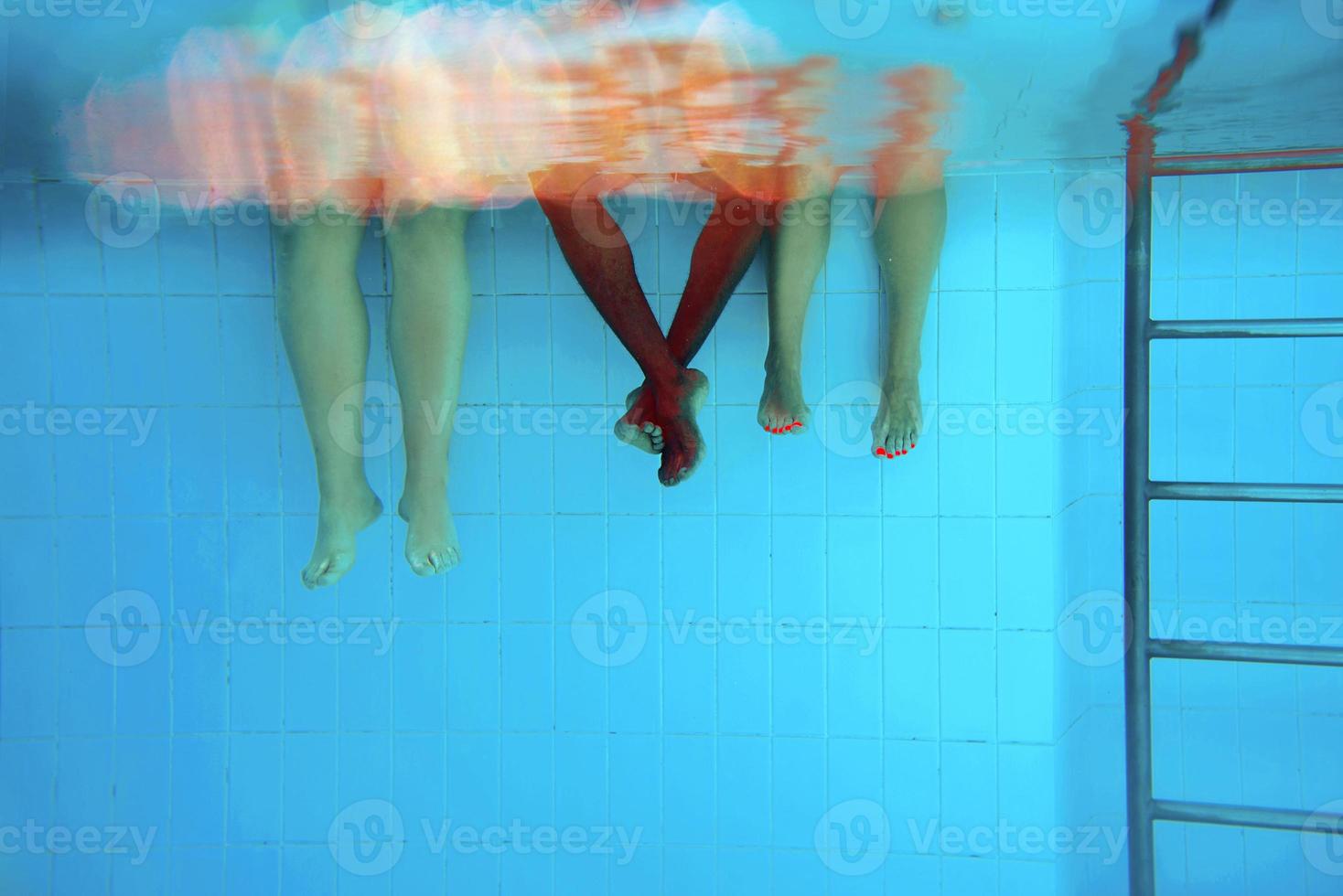 Legs of African American man with caucasian friends in swimming pool underwater. Summer. Vacation, international and sport concept. photo