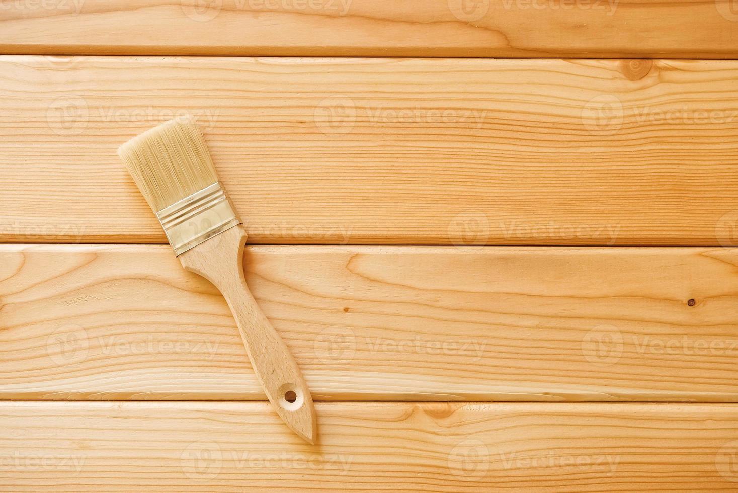 Paint brush with bristles and a wooden handle on natural wooden boards. Top view. Copy, empty space for text photo