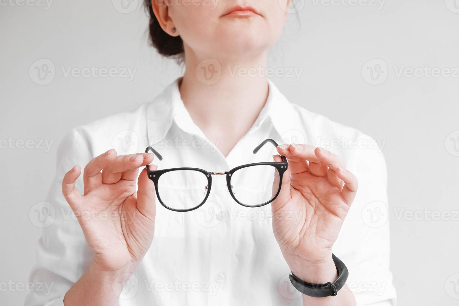 Woman holding optical glasses in a black frame on a white background. Copy, empty space photo