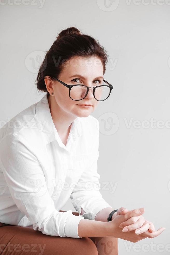 Woman in optical glasses and a white shirt on a white background. Copy, empty space for text photo