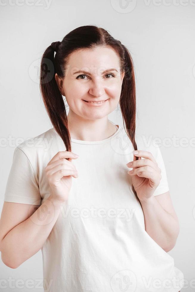 bella mujer con coletas y una cara graciosa con una camiseta de fondo blanco foto