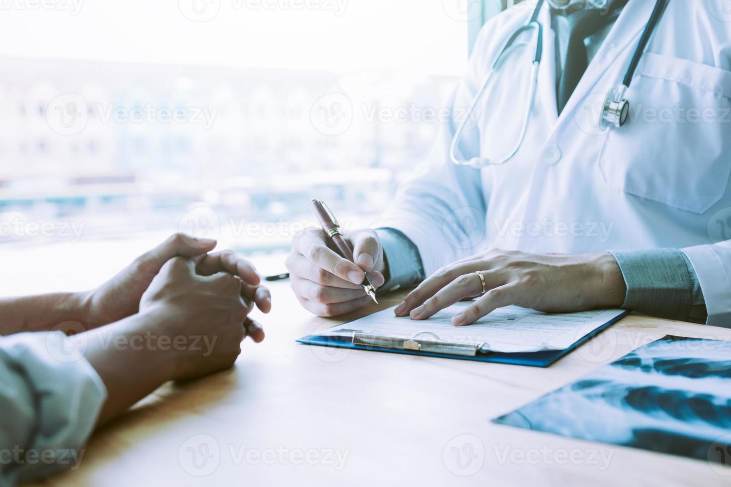 Asian male doctor hand holding pen writing patient history list on note pad. photo