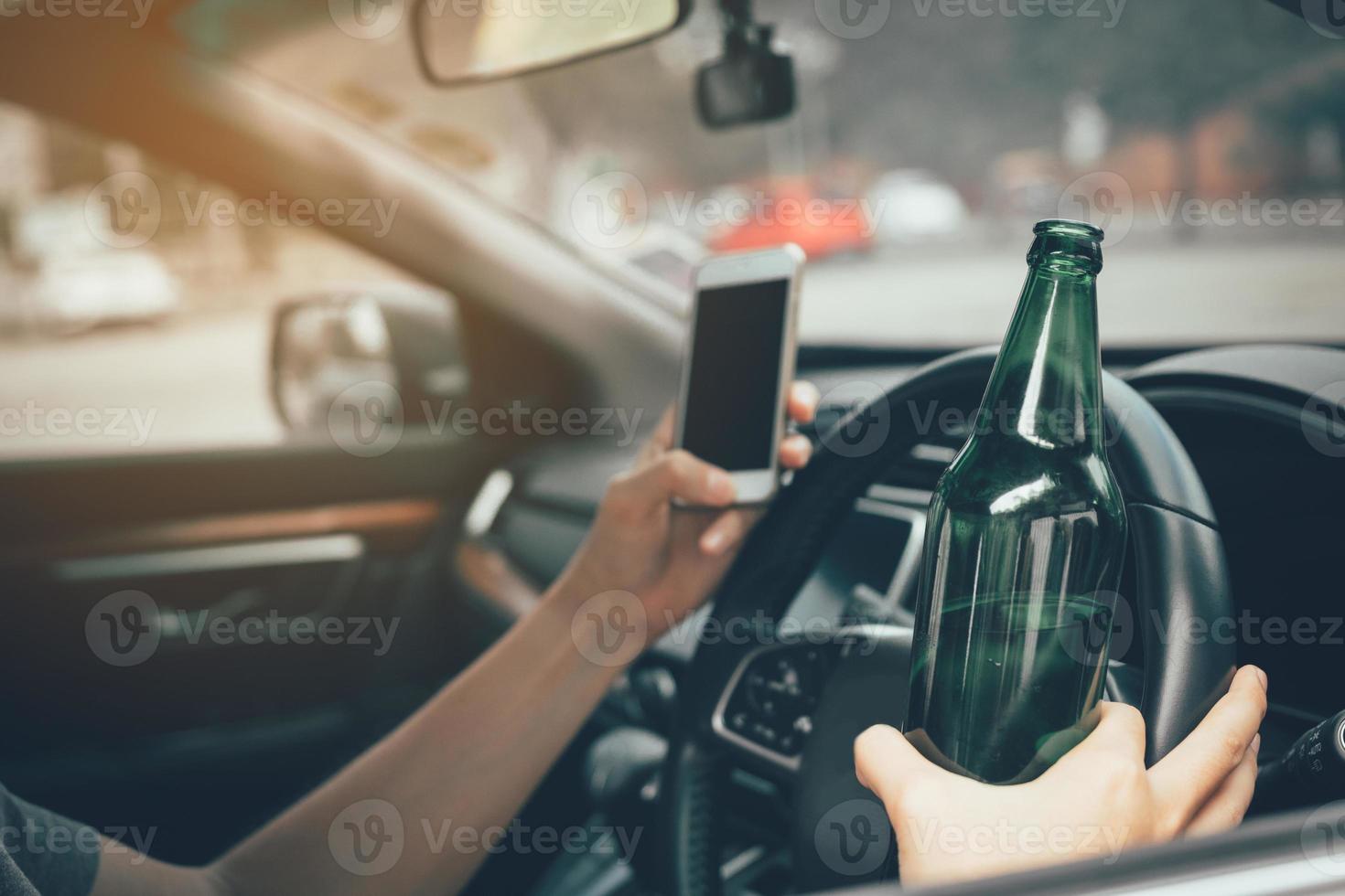 los hombres asiáticos beben alcohol en el auto y usan teléfonos móviles mientras conducen. foto