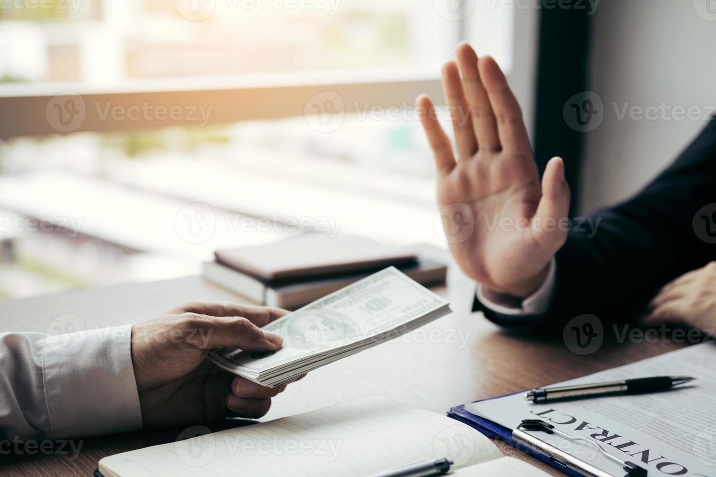 Business person refusing bribe given money by partner with anti bribery corruption concept. photo