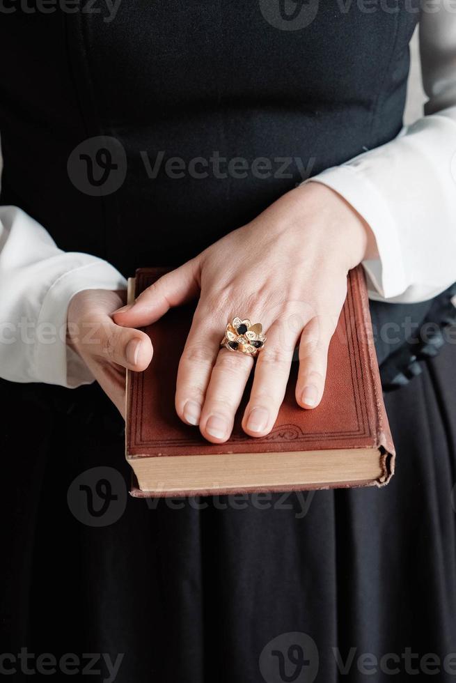 Antique torn book with a hands of a young woman held against black dress. Copy, empty space for text photo