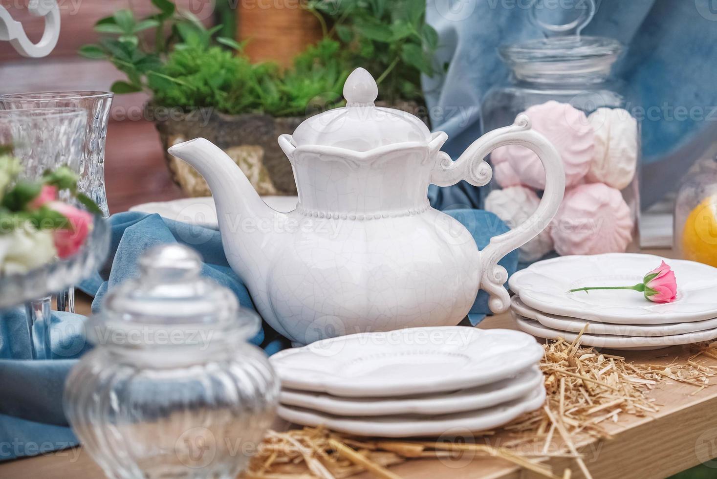 Banquet dessert table decorated with plates, cutlery, glasses, ceramic teapot and flower arrangements. Copy, empty space for text photo