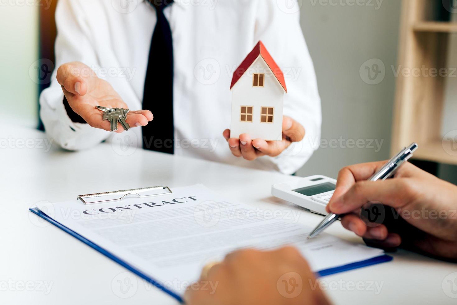 Customer writing signing signature on paper contract with real estate agent and giving key to client. photo