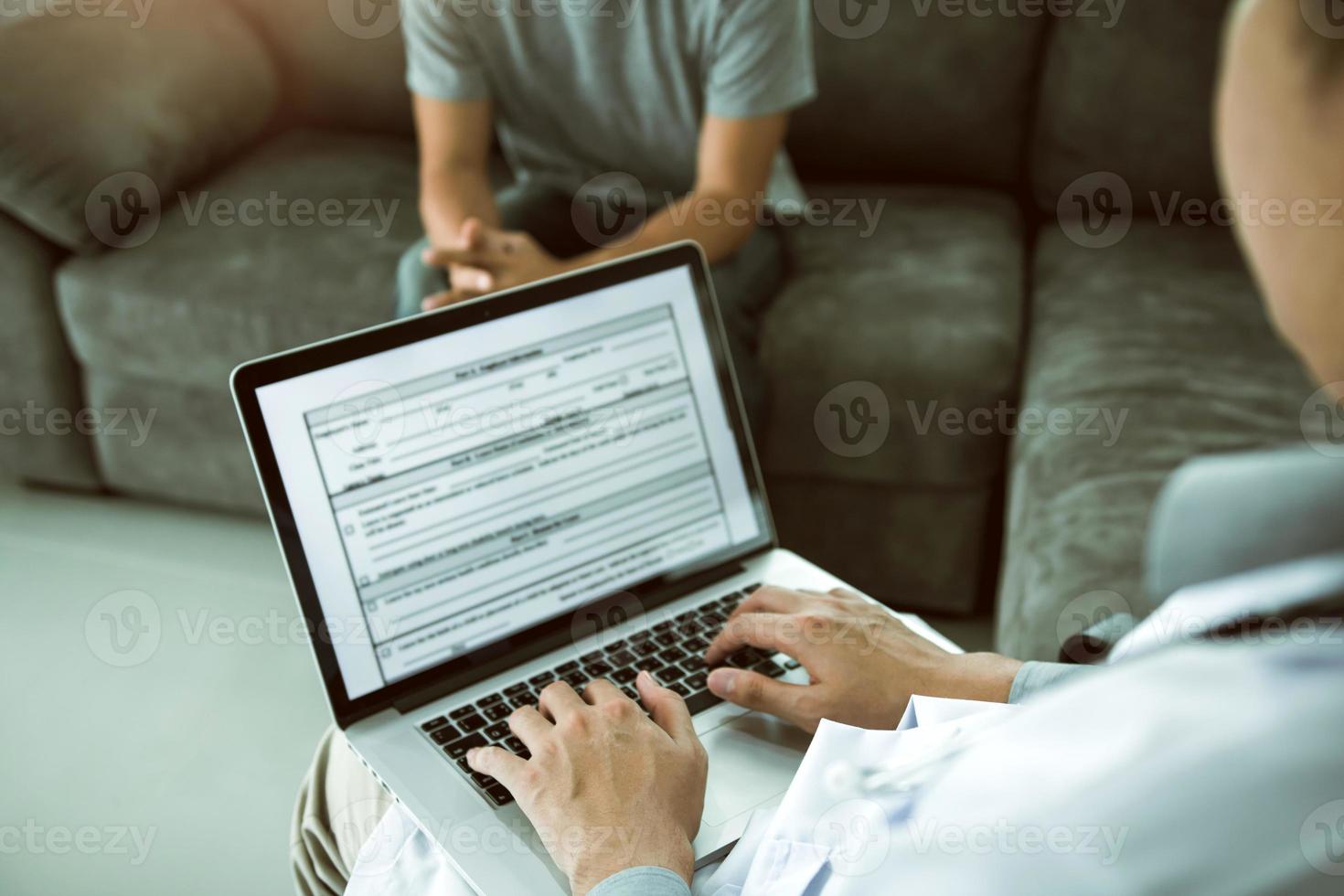 Doctor is using a laptop while typing the patient personal history record and giving advice about the patient home treatment. photo