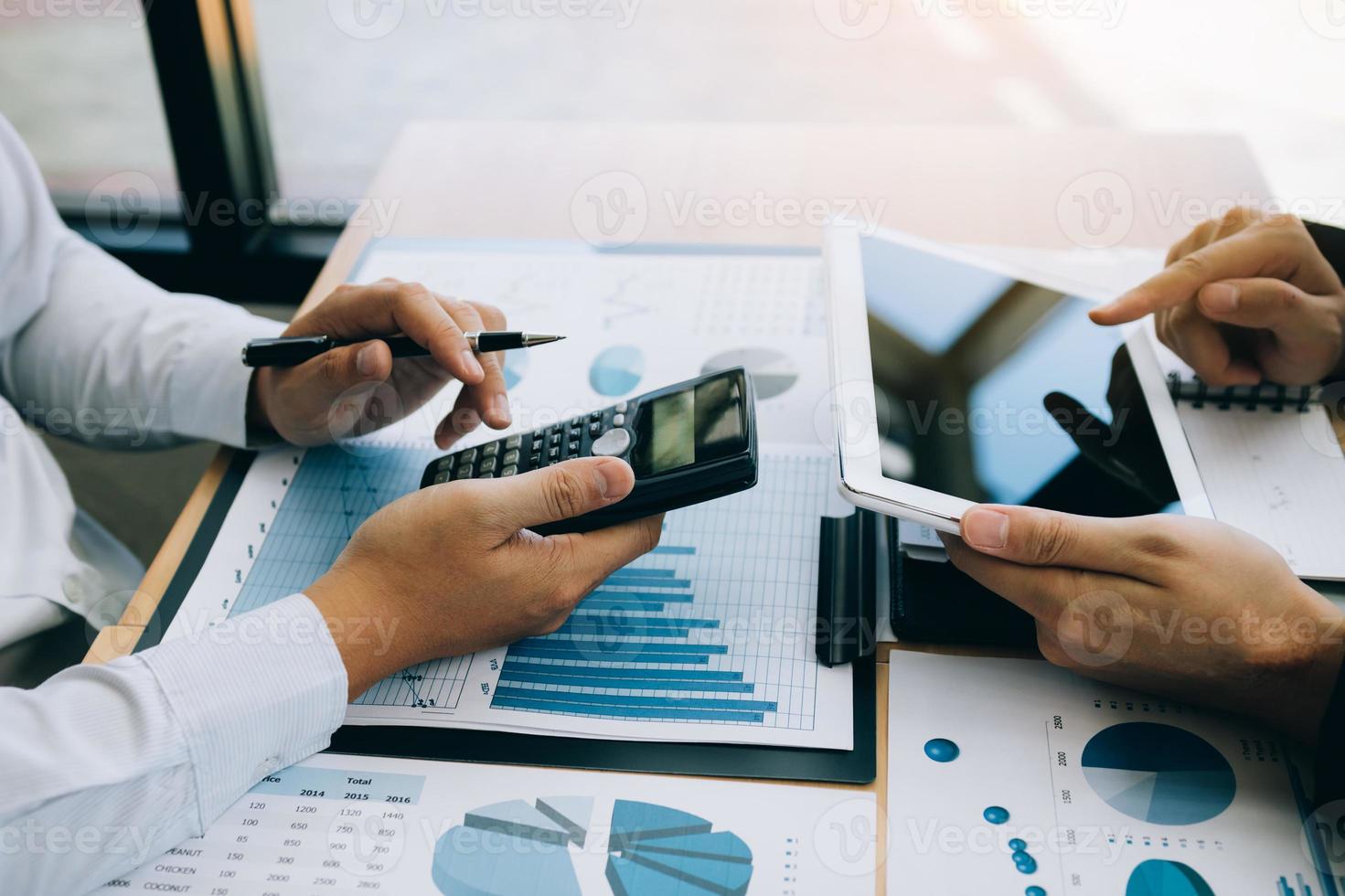 Managers are using tablets to analyze sales cost reports and explain summary reports to employees calculate and record summary information data in the office. photo