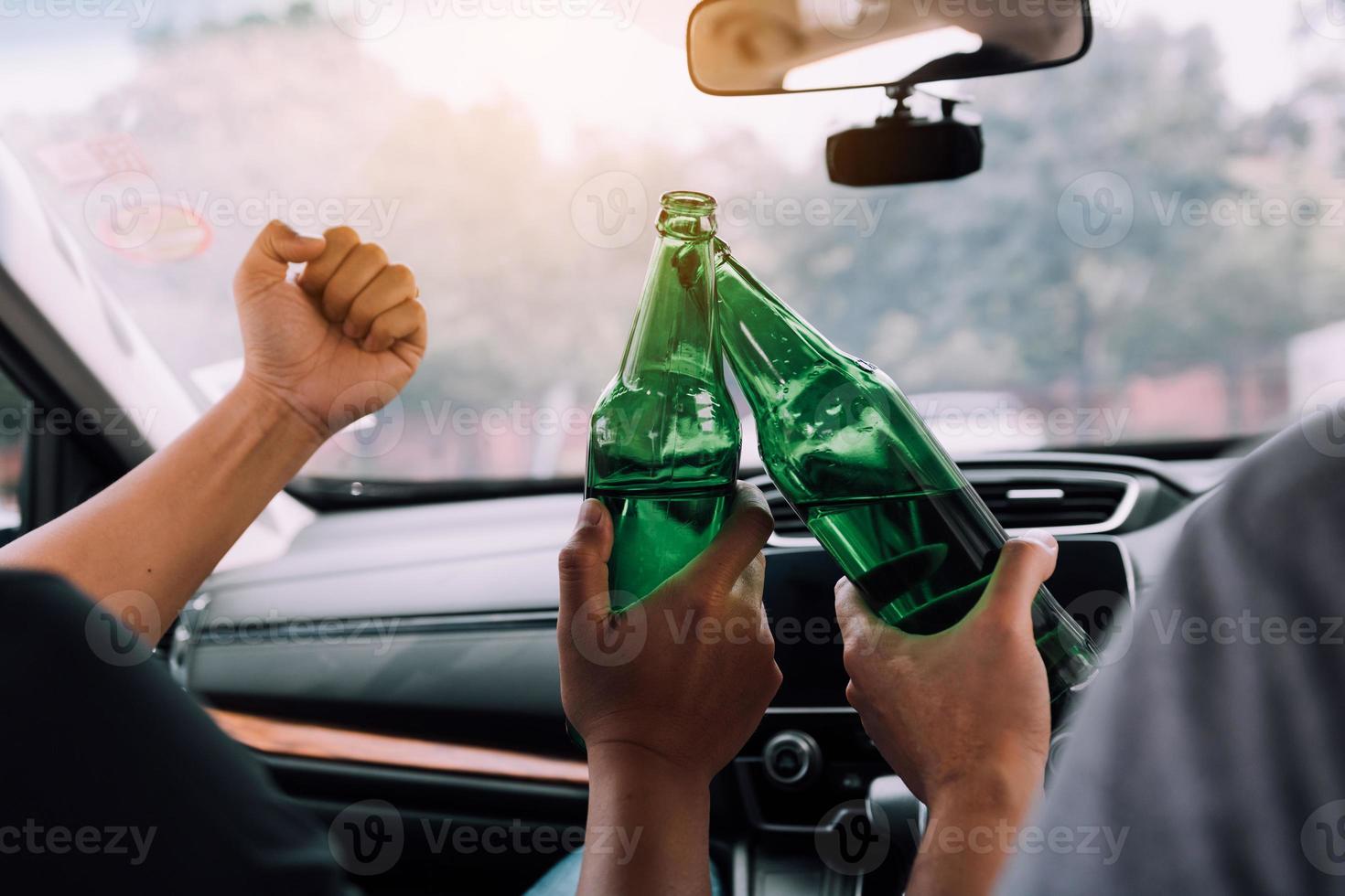 dos amigos varones están celebrando en el auto mientras tocan una botella de cerveza juntos. foto