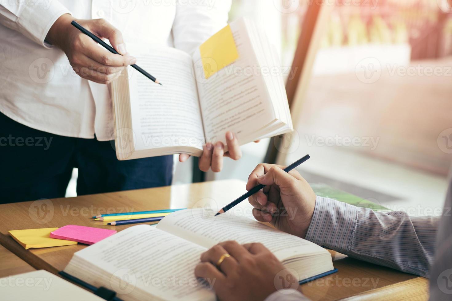 Asian young university students studying together sitting at desk in library. photo