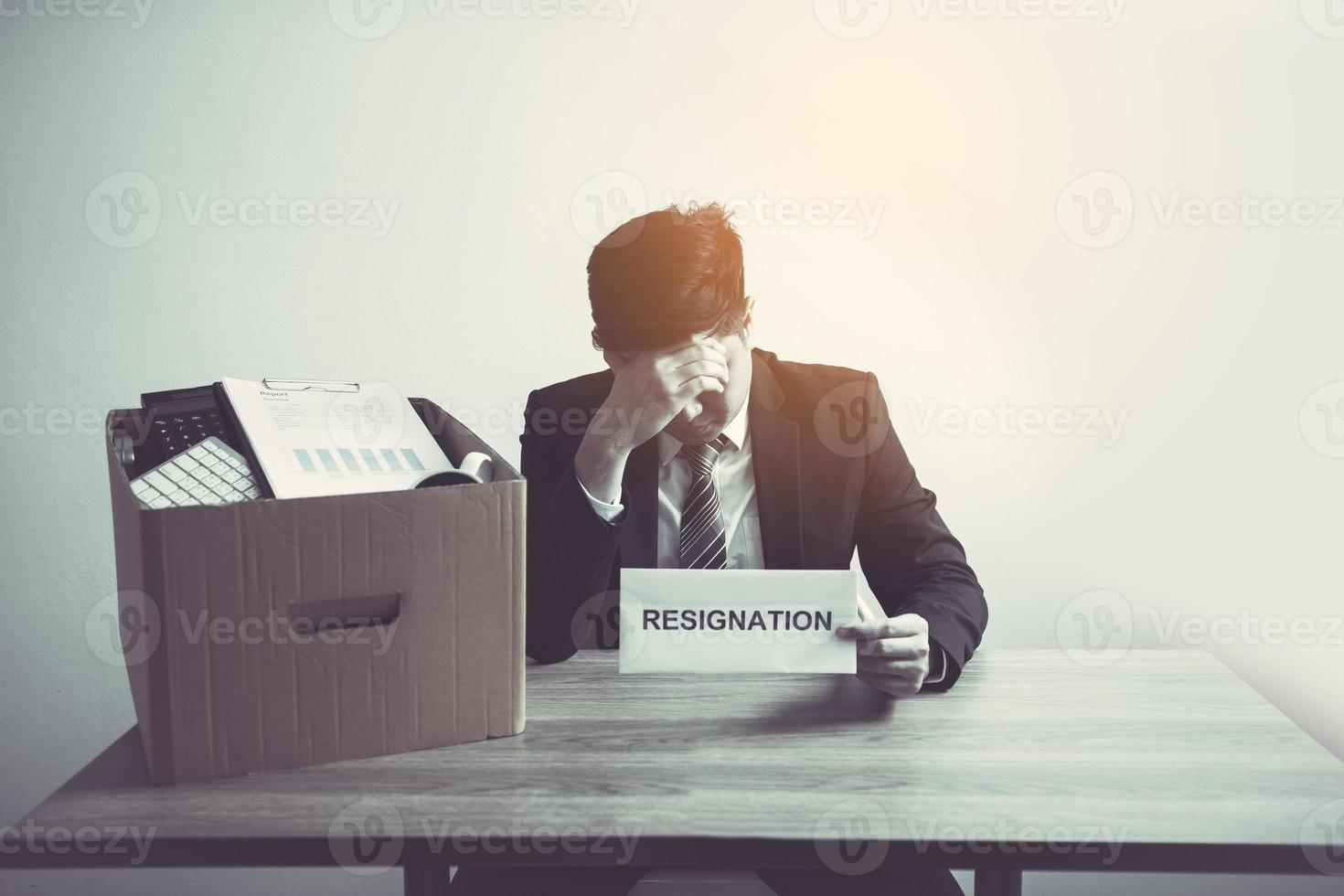 Male employee used his hand to hold the head feeling sad at his desk when he received the contract envelope for resigning from the company. photo