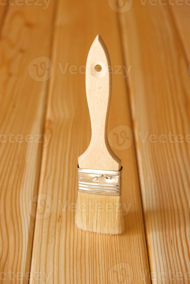 Paint brush with bristles and a wooden handle on background natural boards photo