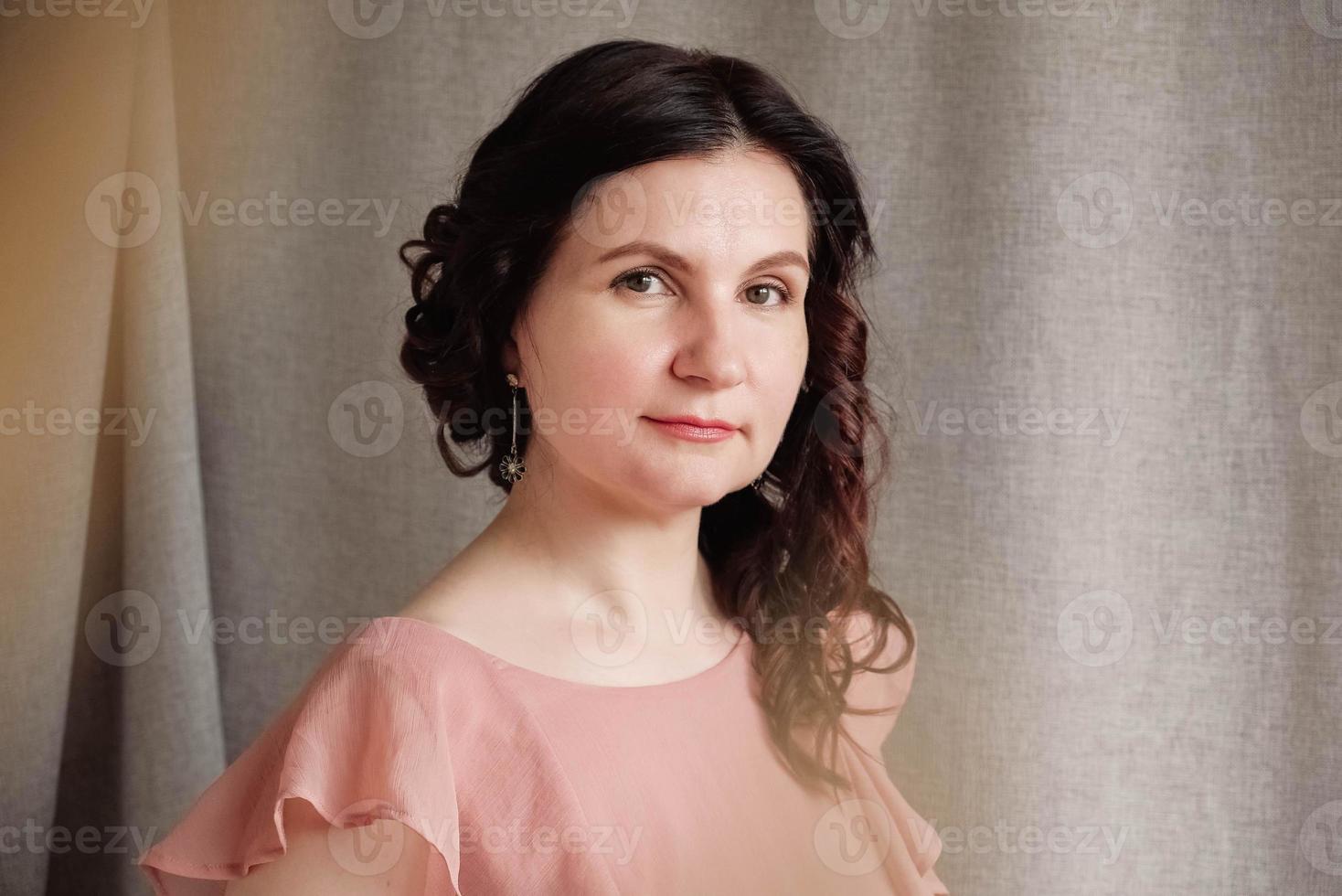 Portrait brunette woman in a pink dress on a background of linen fabric. Copy, empty space for text photo