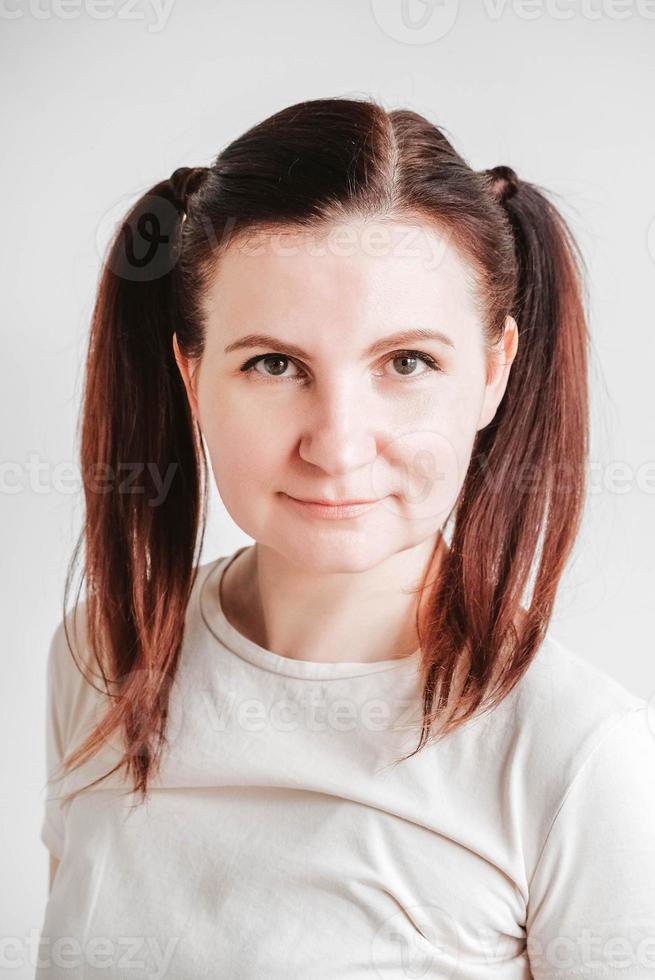 Beautiful woman with pigtails and a funny face wearing a T-shirt on a white background. Copy, empty space photo