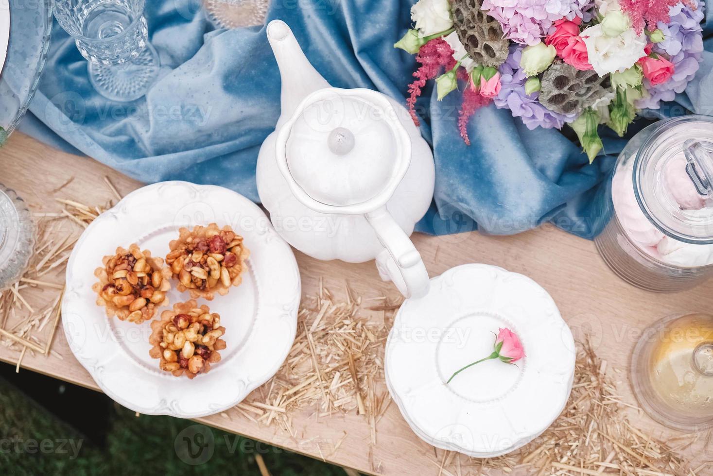 Banquet dessert table decorated with plates, cutlery, glasses, ceramic teapot and flower arrangements. Top view. Copy, empty space for text photo