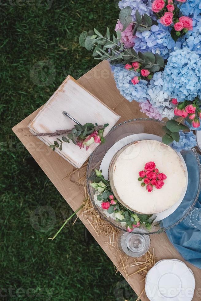 White wedding cake decorated by flowers standing of festive table. Top view. Copy, empty space for text photo