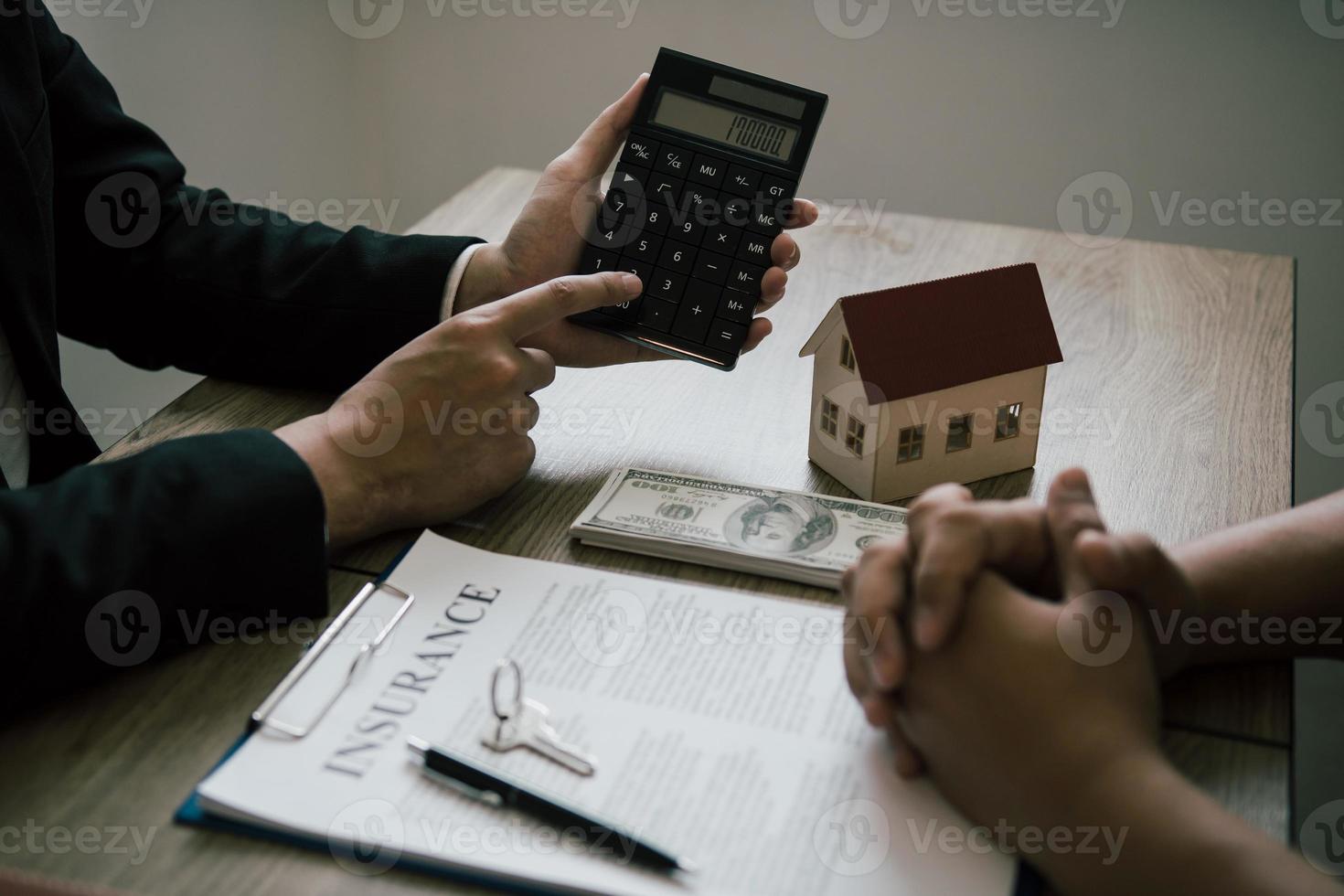 los agentes están calculando la tasa de pago del préstamo o el monto de las primas de seguro para los clientes que vienen a ponerse en contacto con la compra de una nueva casa en la oficina. foto