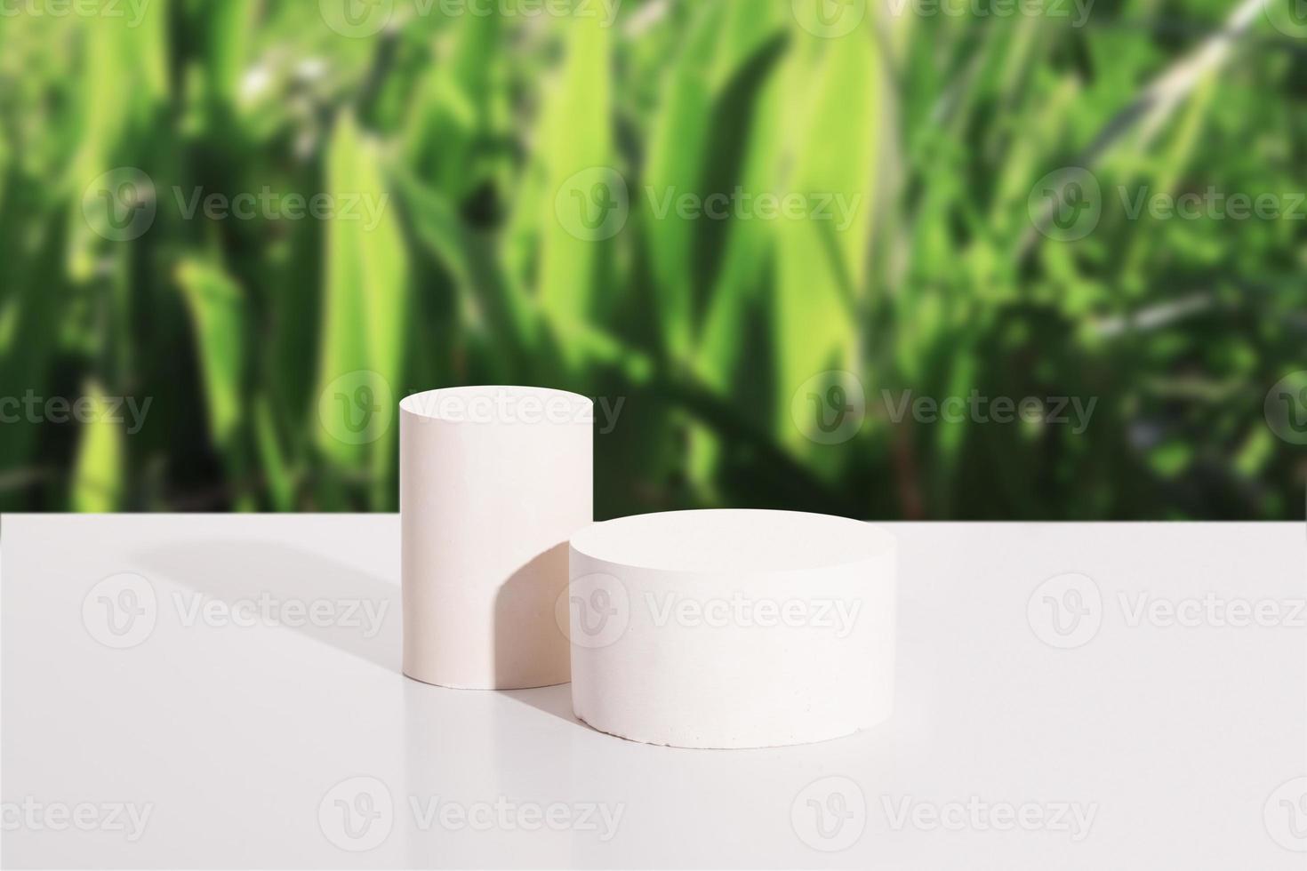 Empty cylindrical podium or pedestal on white background with green grass. Blank shelf product standing background photo