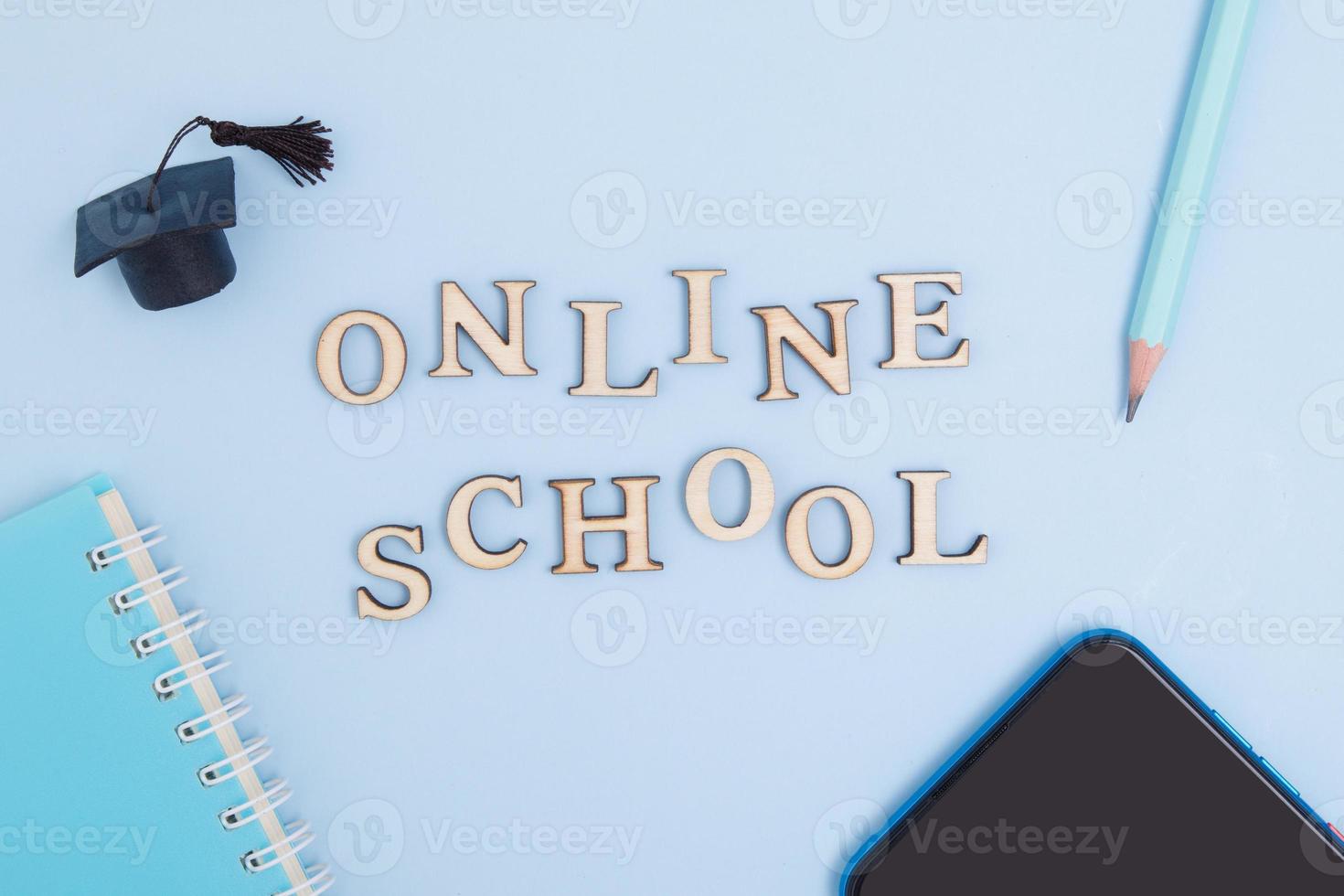 Conceptual layout about the modern education system. School online text and smartphone, writing equipment and graduate cap photo