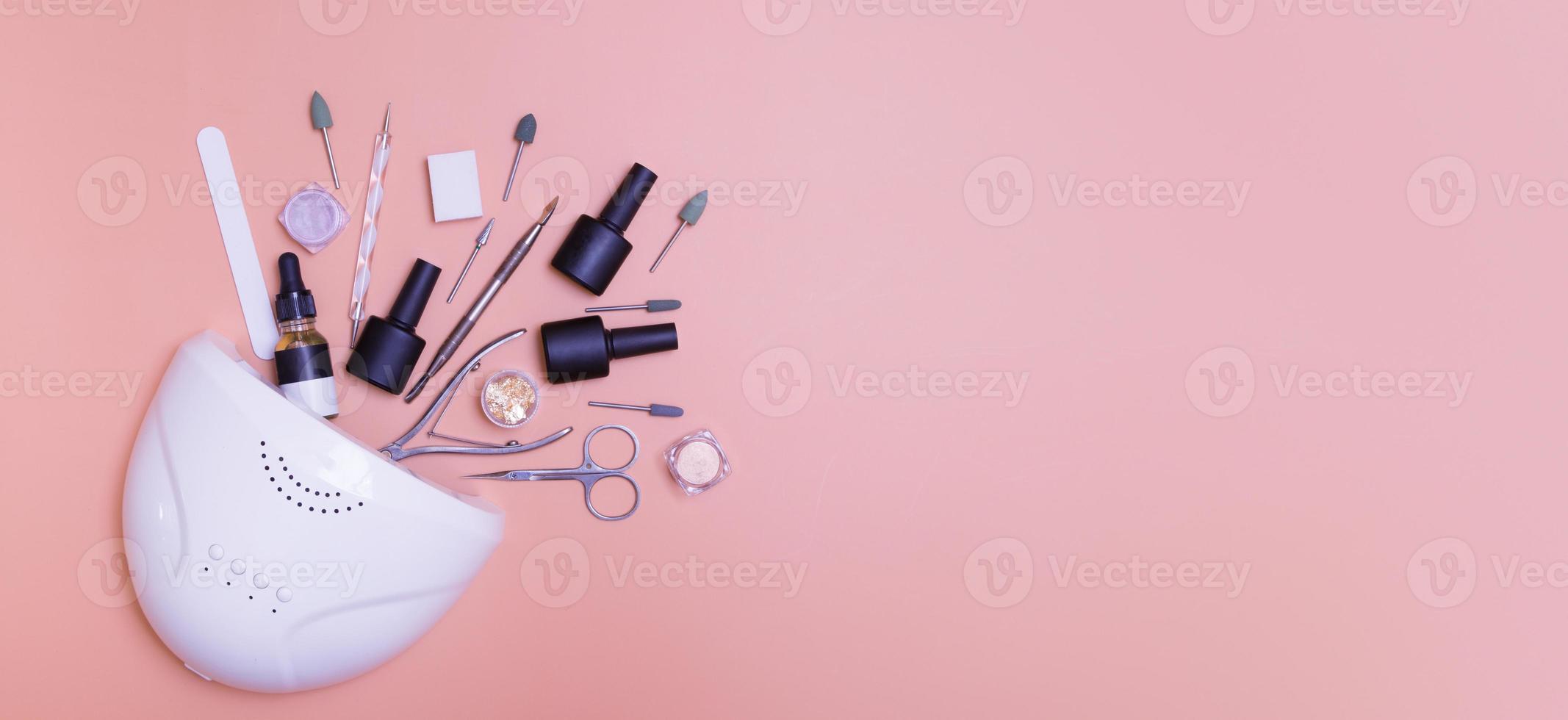 Banner with manicure lamp and tools for applying varnish top view on colored background. Salon manicure concept photo