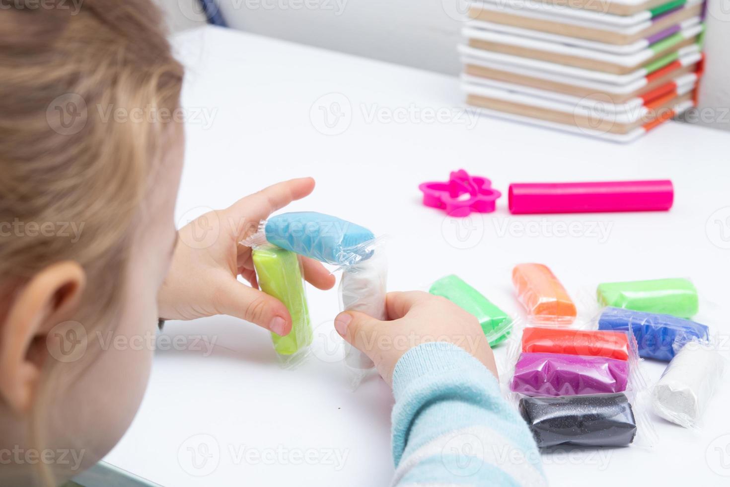 The girl at the table is playing with modeling dough. Childrens games for fine motor skills photo