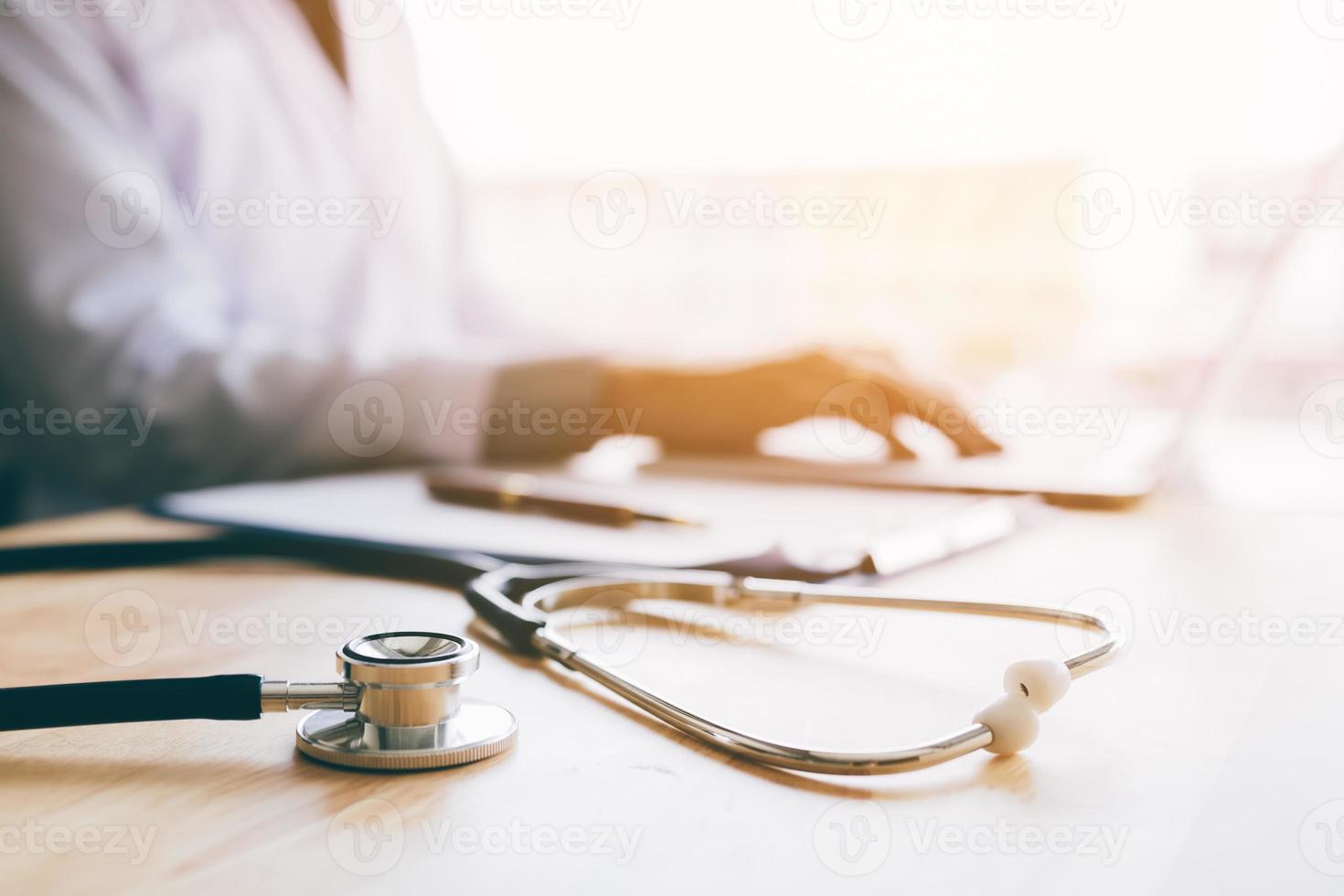 Doctor using laptop at desk in clinic working on computer at room office. photo