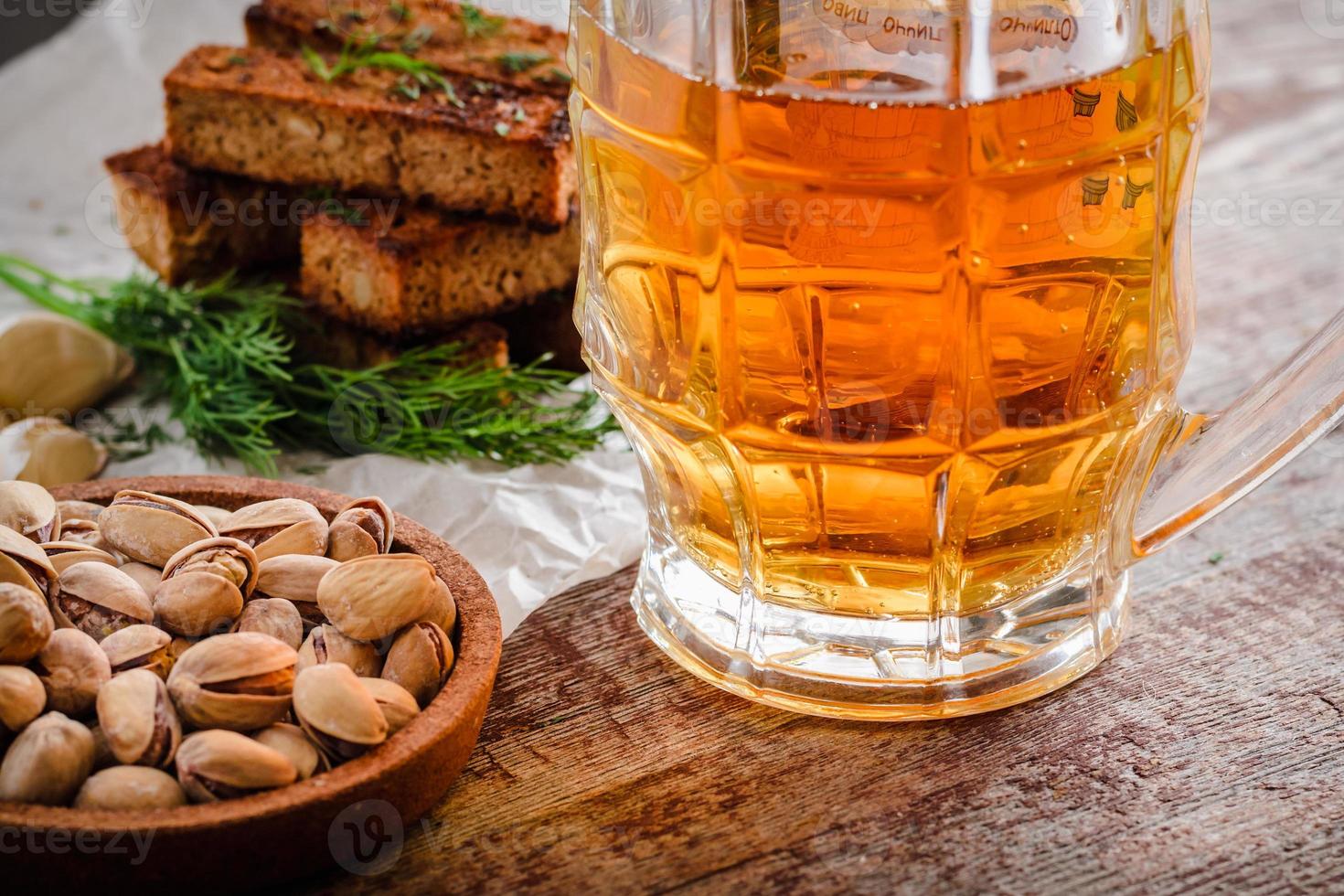 mug of light beer and snacks on wooden table photo