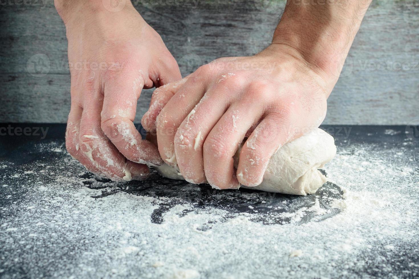 man kneads dough with his hands photo