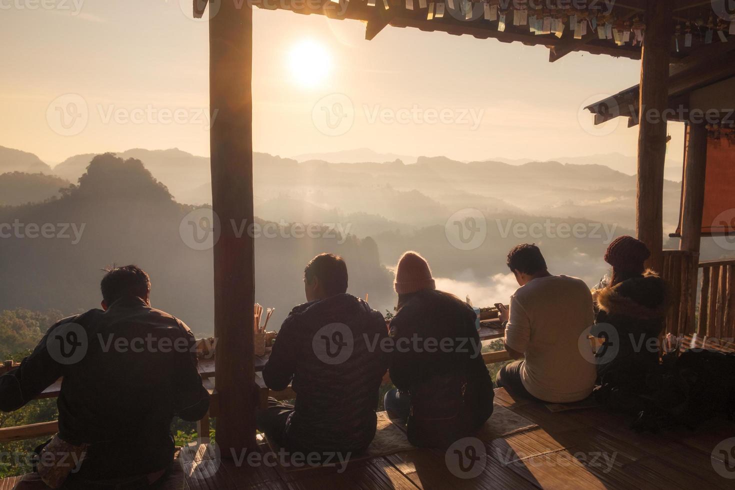 Tourists sitting on wooden terraced with sightseeing view sunrise on mountain photo