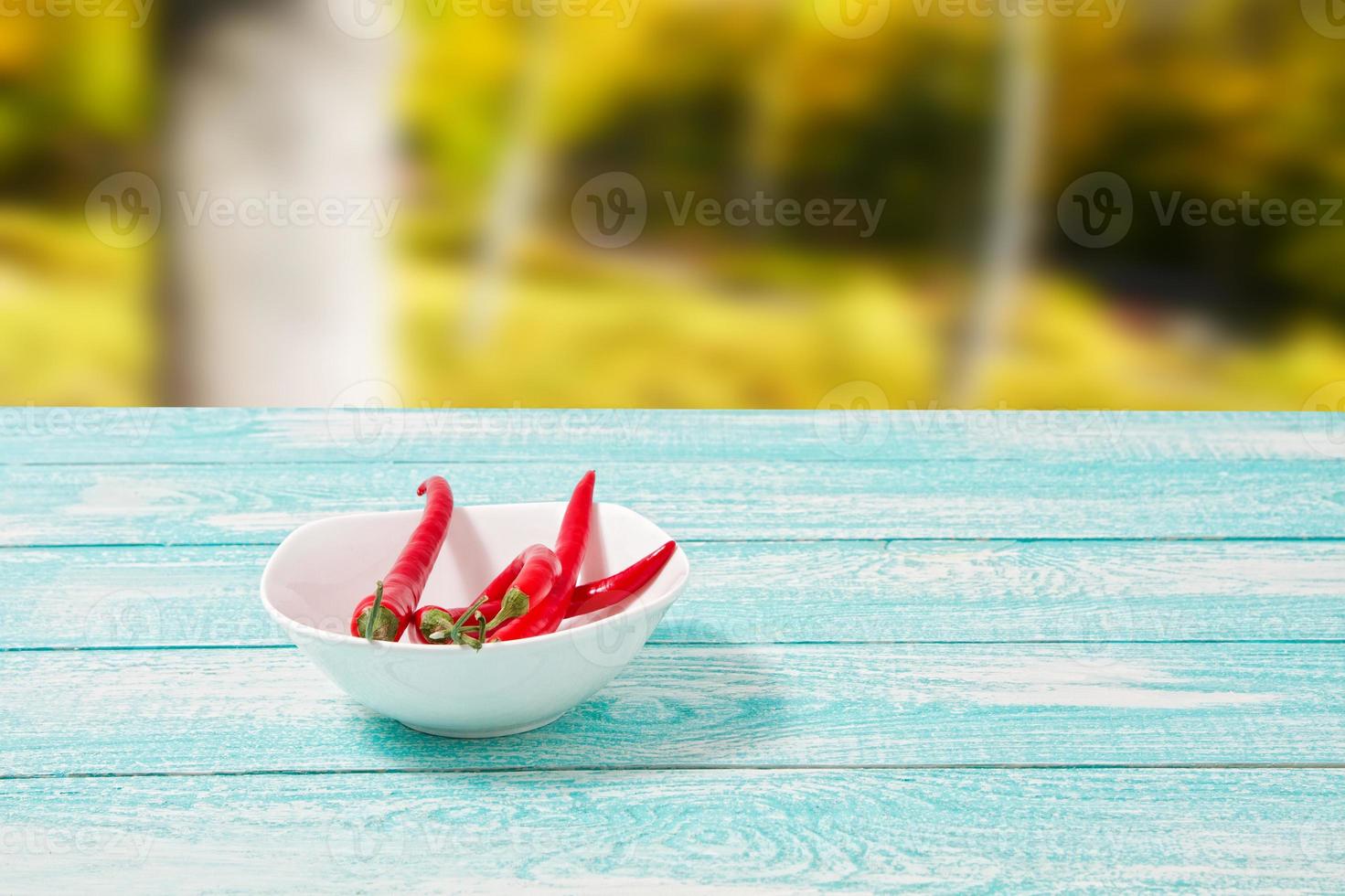 Decoration of red hot chili pepper on blue wodden board on blurred park background. Set,copy space,mock up. Cayenne on white plate photo