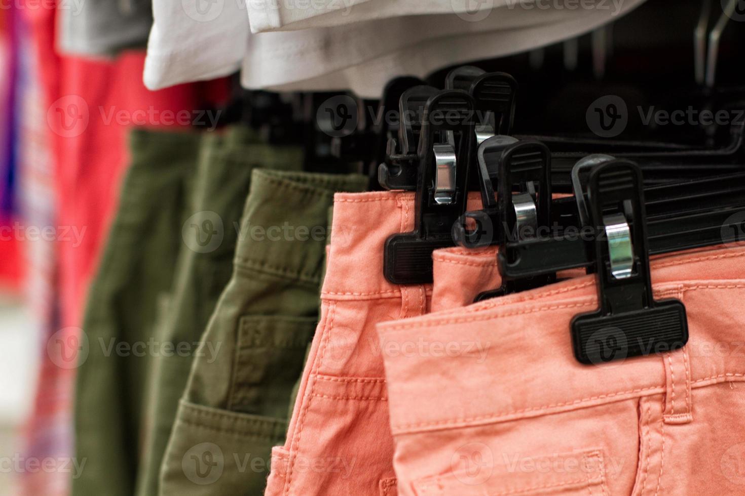 Some used clothes hanging on a rack in a flea market. Background of dress. Selective focus. photo